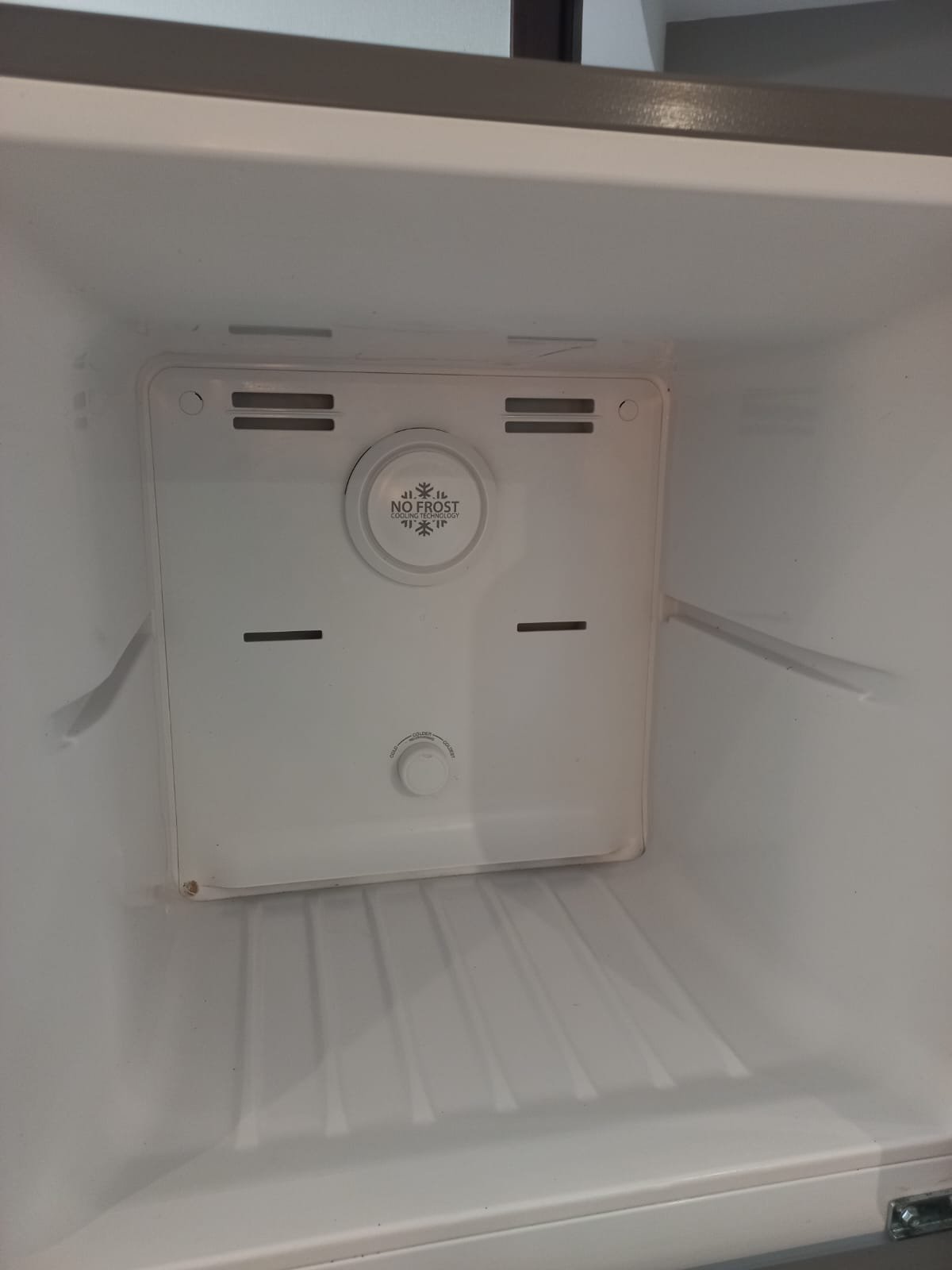 Interior of a clean refrigerator with a "No Frost" label and temperature dial.