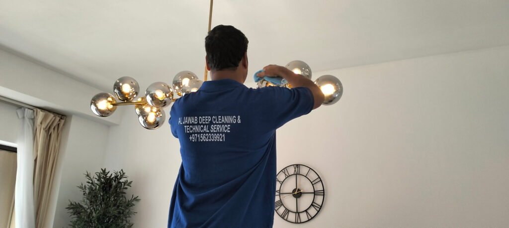 Man cleaning modern chandelier, Al Jawab Deep Cleaning & Technical Service